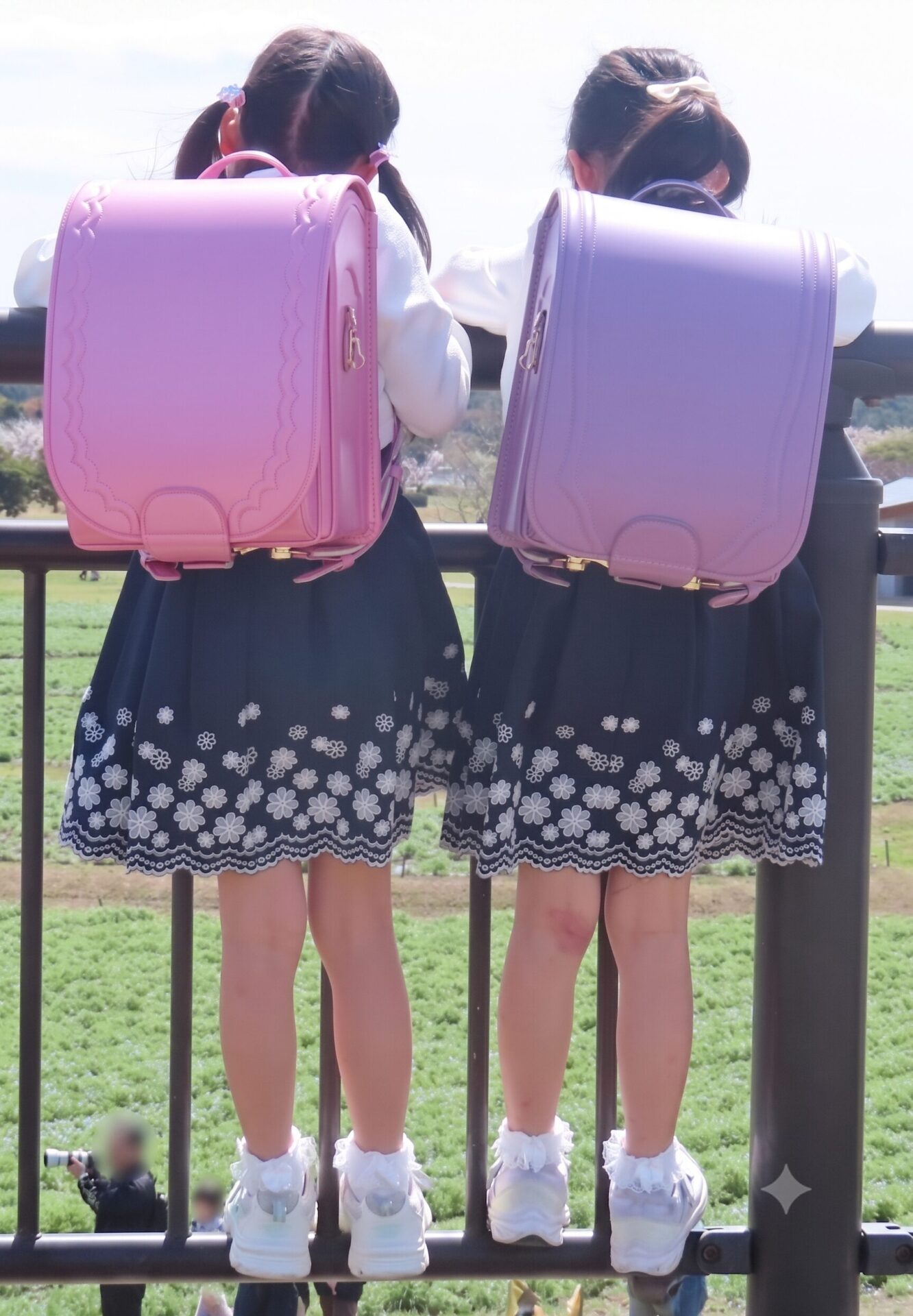 桜の季節、ランドセルを背負って並ぶ双子の娘たち