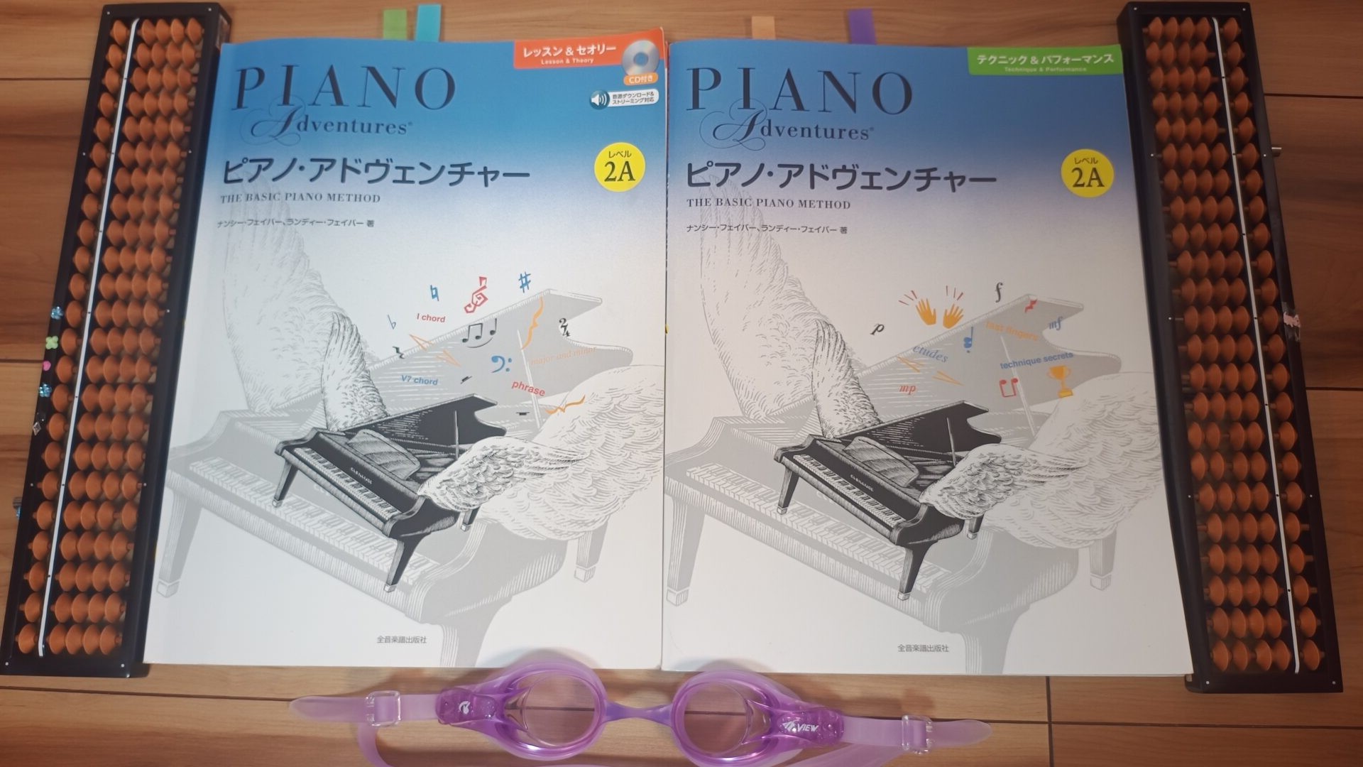 双子の習い事の道具。そろばん2台とピアノの教本2冊、スイミングのゴーグルが並んでいる